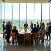 Lideri internaționali într-o sală luminoasă cu geamuri și turbine eoliene